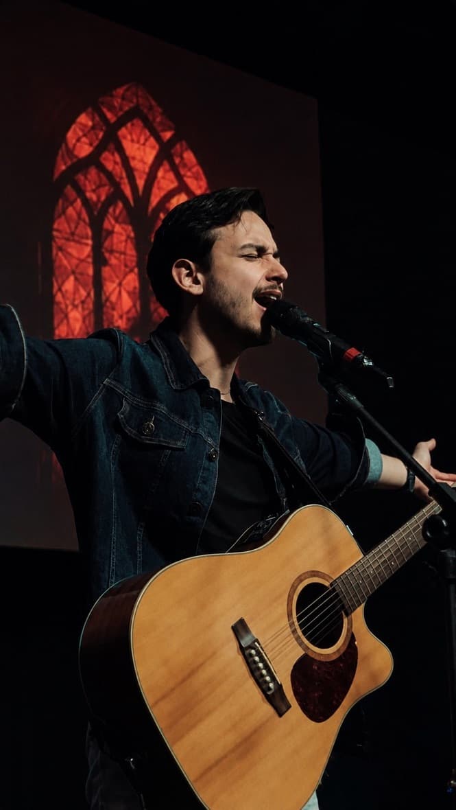 Pedro leading worship on stage, guitar in hand