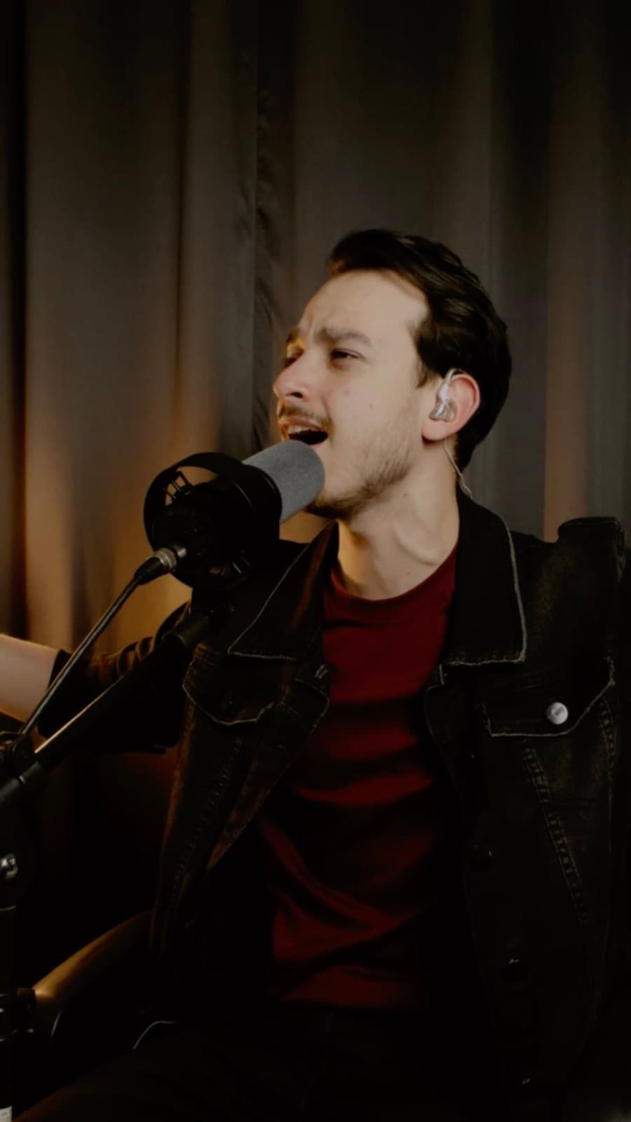 Pedro singing into a studio microphone wearing in-ear monitors